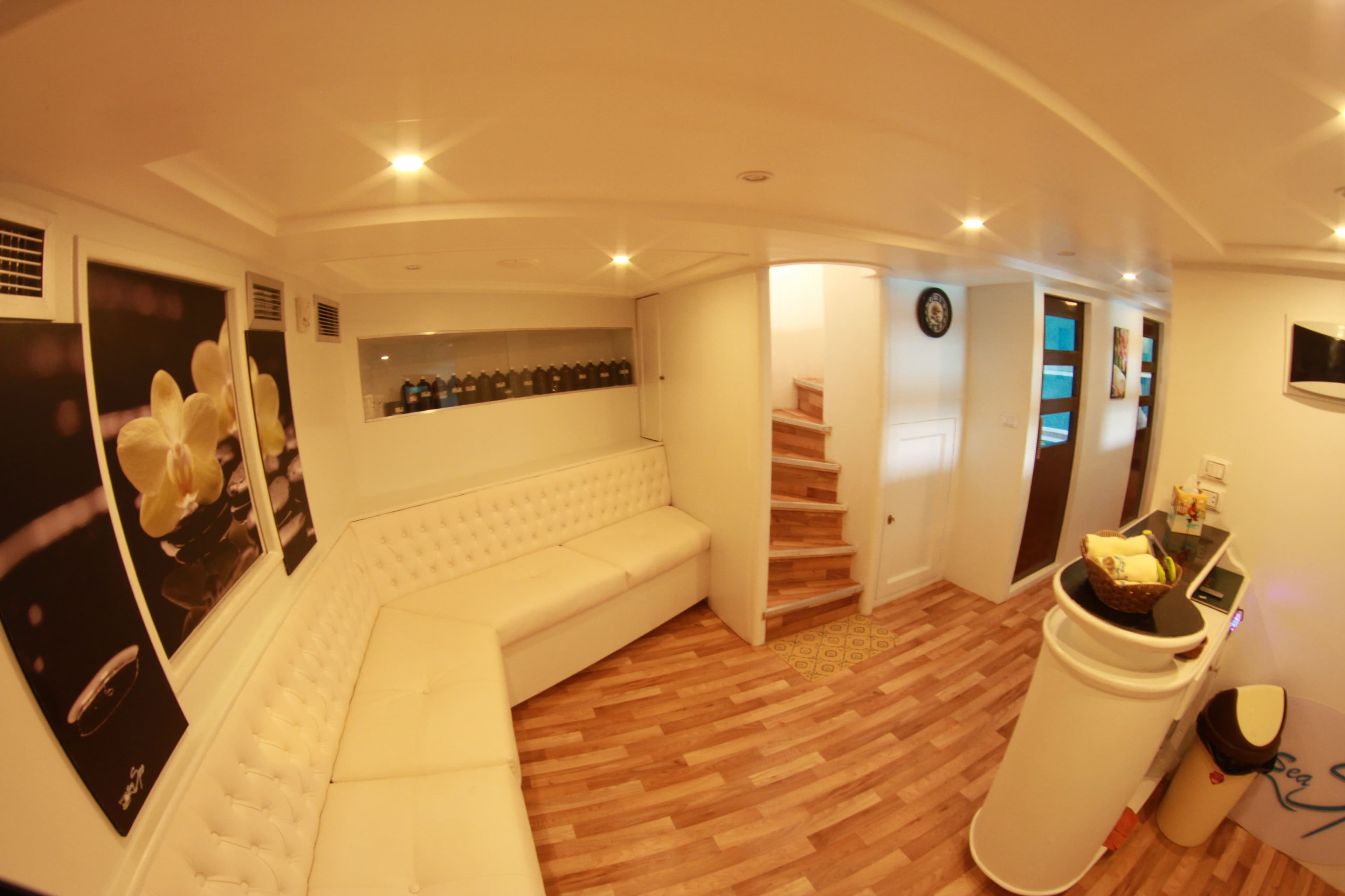 Lower-deck lounge with tufted bench seating and stairs to the upper deck