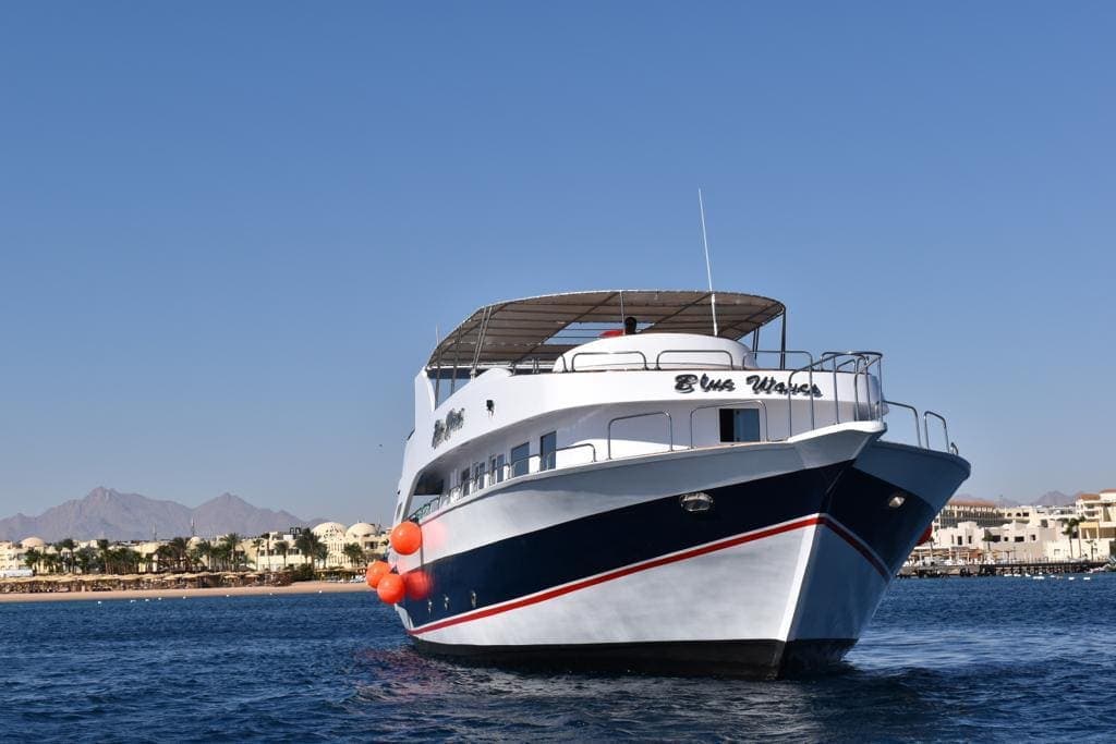 The Blue Waves boat bow-on with the Hurghada coast and mountains behind