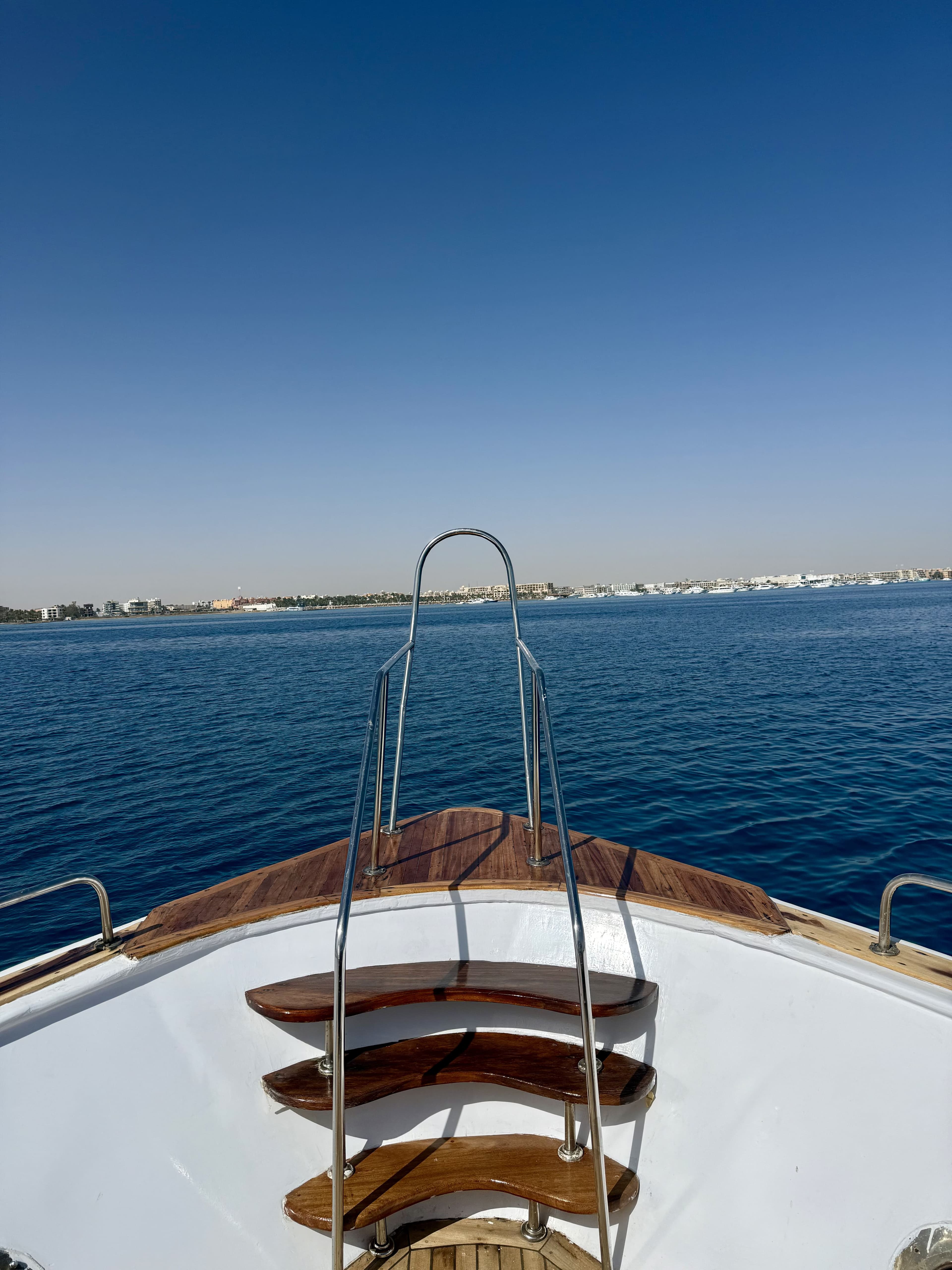 View past the boat's bow rail toward the Hurghada hotel coastline